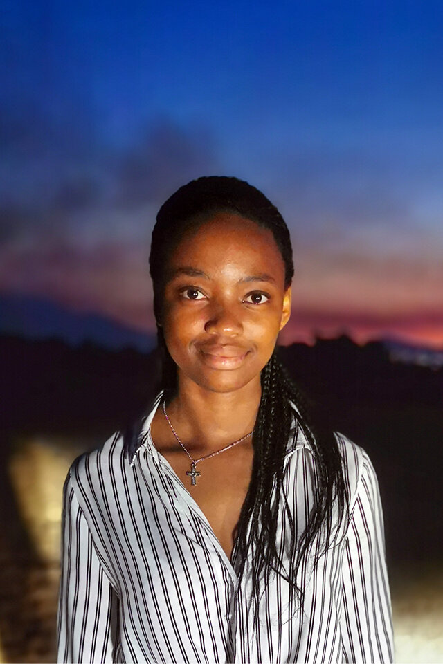 Portrait einer jungen afrikanische Frau im Sonnenuntergang, die in die Kamera lächelt.